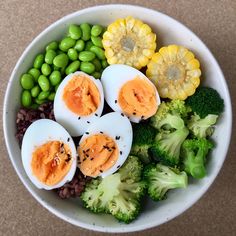 a bowl filled with eggs, broccoli and other vegetables on top of a table