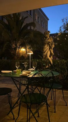 an outdoor dining area with table, chairs and lamp in the dark night time setting