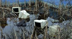 there are four old tvs in the water and one is broken down with it's doors open