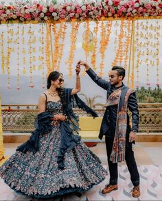 a man and woman standing next to each other in front of a floral decorated stage