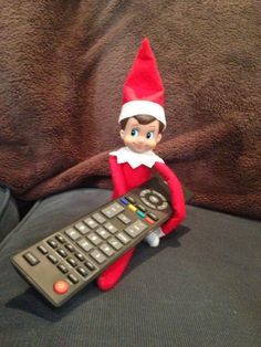 an elf with a remote control sitting on top of a couch next to a keyboard