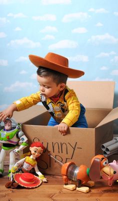 a young boy playing with toy toys in a cardboard box