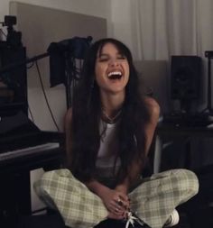 a woman is laughing while sitting on the floor in front of a set of musical equipment