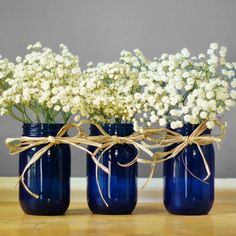 three blue mason jars with baby's breath tied to them