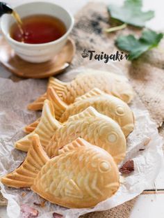 three fish shaped cookies sitting next to a cup of tea