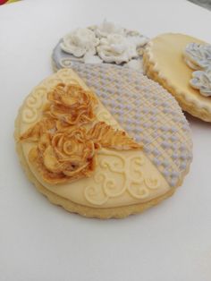 three decorated cookies sitting on top of a white table next to each other with flowers