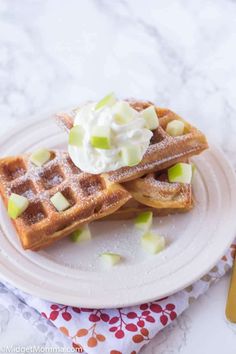 two waffles on a white plate with whipped cream and apple slices in the middle