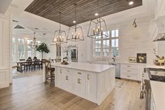 a large kitchen with an island in the middle and lots of lights hanging from the ceiling