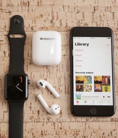 an apple watch, headphones, and ear buds are on the table next to each other