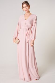 Warm and inviting, the Wholehearted Maxi Dress is a perfect combination of modest and sultry. Long balloon sleeves frame a surplice neckline separated by a tie at the waist, creating a forgiving faux wrap. The skirt maintains an airy and flowy shape that trails behind as you walk down the aisle. - Chiffon- Faux wrap- Keyhole- Elastic waist- Comes in 14 ColorsSize + Fit - Model is 5'9" and wearing size XS- Measurements taken from size S - Chest: 35"- Length: 63 1/4" Fabric Self: 100% PolyesterLin Evening V-neck Faux Wrap Dress, Elegant V-neck Faux Wrap Dress, Solid Long Sleeve Wrap Dress For Formal Occasions, Modest V-neck Formal Dress, Modest Fitted V-neck Maxi Dress, Pink V-neck Dress With Surplice Neckline For Formal Occasions, Feminine Fitted Maxi Dress With Tie Waist, Feminine Fitted Wrap Dress, Feminine Wrap Dress With Surplice Neckline For Date Night