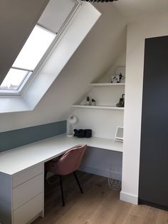 a white desk sitting under a skylight in a room next to a wooden floor