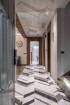 a long hallway with white and grey tiles on the floor, leading to an elevator