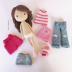 crocheted doll clothes and accessories are laid out on a white surface, with the doll's hair pulled back