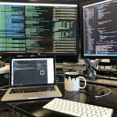 two computer monitors sitting on top of a desk next to a keyboard and monitor screen