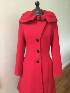 "There's lots of style tailored into this lovely red coat by Venus! The wide round shaped collar is slightly gathered and can be worn up or down. It has a small buckle closure at the neck that is pretty awesome! The waist is fitted with a stitching detail. There are inset pockets that are lined and the shoulder pads add to the silhouette. The fabric is a soft polyester that looks like wool, and the red color is vibrant. The red is on the garnet side of red not the tomato/orange side. Vintage siz Red Fitted Collared Outerwear, Chic Red Collared Outerwear, Red Long Outerwear With Buttons, Long Red Outerwear With Buttons, Red Lapel Collar Outerwear For Winter, Fitted Vintage Red Outerwear, Chic Long Red Outerwear, Chic Red Long Outerwear, Red Fitted Long Coat