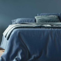 a bed with blue sheets and pillows in a room