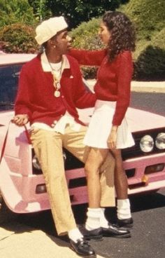 a man and woman sitting on the hood of a pink car