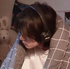 a person with headphones on sitting in front of a teddy bear