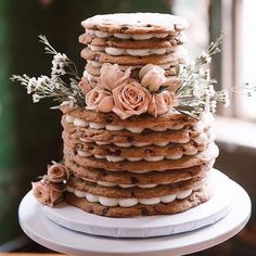 a tall stack of cookies sitting on top of a white cake plate covered in frosting