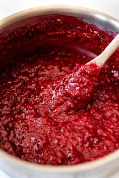 a wooden spoon in a pot filled with cranberry sauce on top of a table