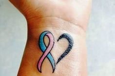 a small wrist tattoo with a pink and blue ribbon on it's left side