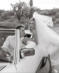 a bride and groom leaning out the window of a car