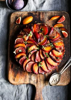 a wooden cutting board topped with sliced plums