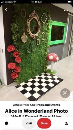 a green wall covered in moss and red flowers next to a black and white checkered floor