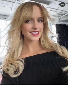 a woman with blonde hair is smiling and wearing a black sweater in an office setting