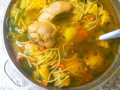 a bowl of soup with chicken, corn and noodles