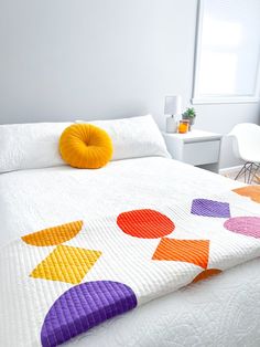 a white bed topped with a colorful quilt