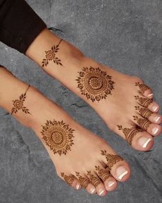 two feet with henna tattoos on them, one has an intricate design and the other has