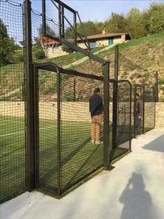 two men are standing in front of a fence on the side of a soccer field