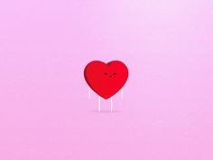 a red heart lollipop sitting on top of a pink surface with two eyes