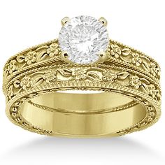 a yellow gold wedding ring set with a round diamond in the center and filigrees on each band