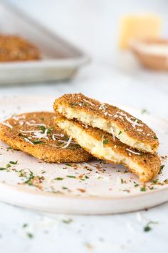 two fried food items on a plate with parmesan sprinkles and seasoning