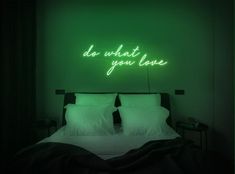 a bed in a room with a neon sign above it that says do what you love