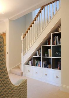 a living room with bookshelves and a stair case in front of the stairs