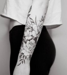 a woman's arm with flowers and leaves tattooed on the left side of her arm