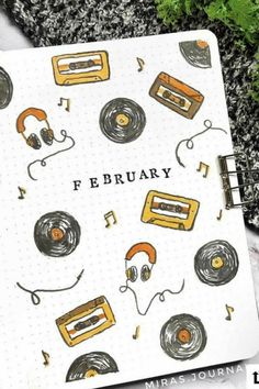 an open notebook with headphones on it and the words february written in black ink