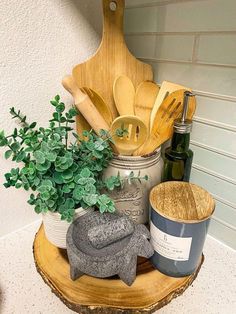 an assortment of kitchen utensils sitting on top of a wooden stand next to a potted plant