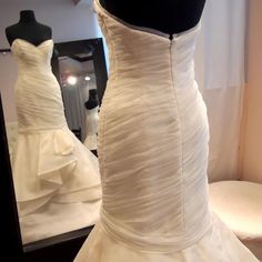 a wedding dress on display in front of a mirror