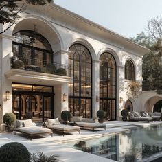 a large white house with an outdoor pool and lounge chairs in front of the building