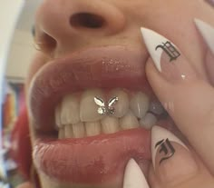 a close up of a person's mouth with tattoos on her fingers and teeth