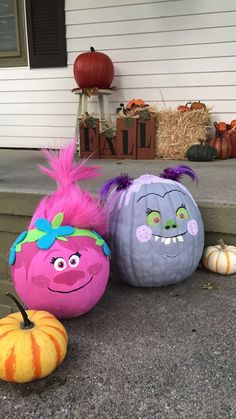 three pumpkins with faces painted on them sitting in front of a house