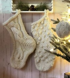 two knit stockings hanging on a wall next to a christmas tree