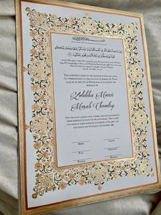 an ornate wedding card with gold trimmings and flowers on the border is displayed