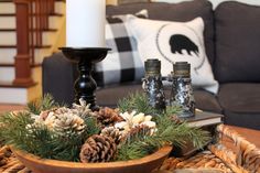 a coffee table with pine cones, candles and other decorations on it in front of a couch