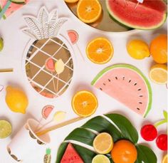 various fruits and vegetables cut out on a white surface with pineapples, watermelon, oranges, cherries, lemons