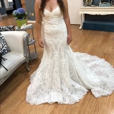 a woman in a white wedding dress standing on a wooden floor next to a couch